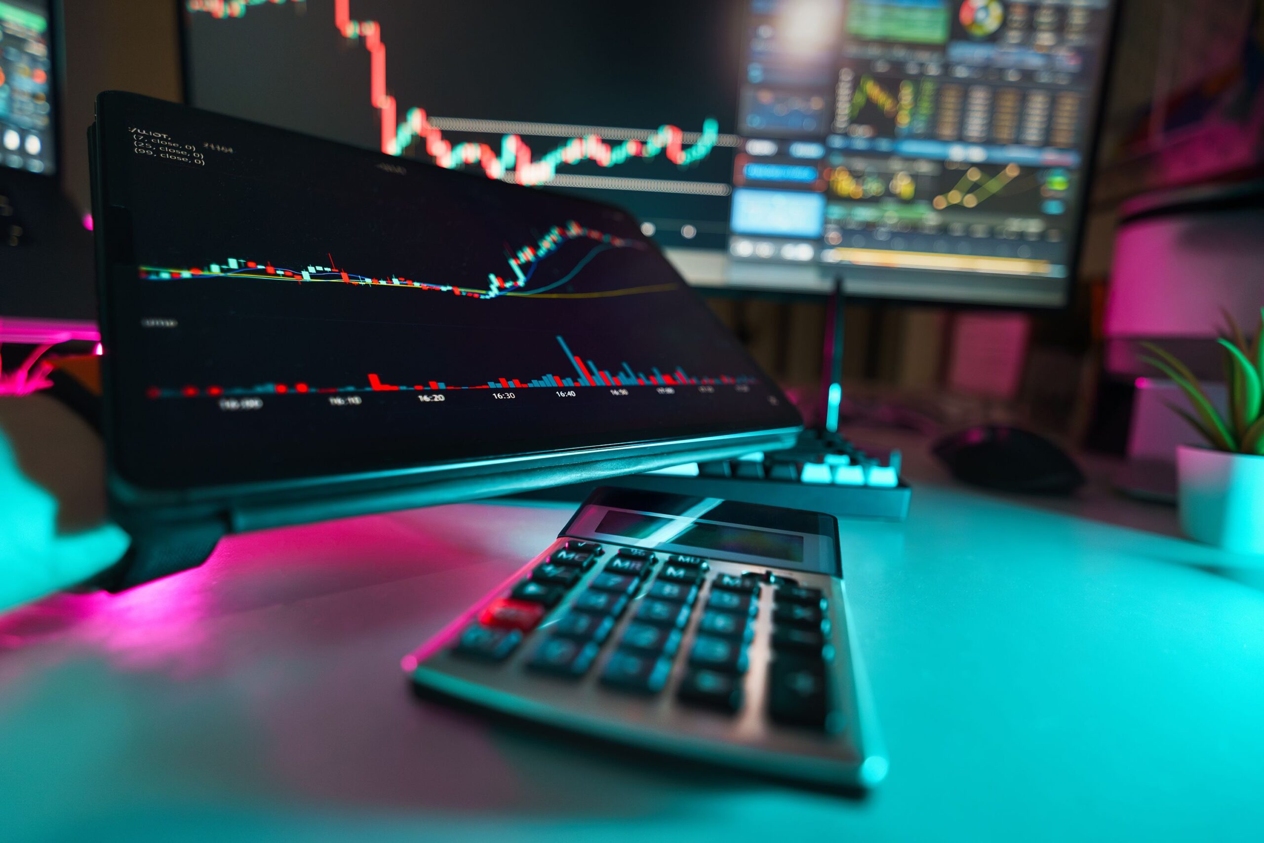 A vibrant office setup with digital tablets displaying financial analysis and stock charts, complemented by a calculator.
